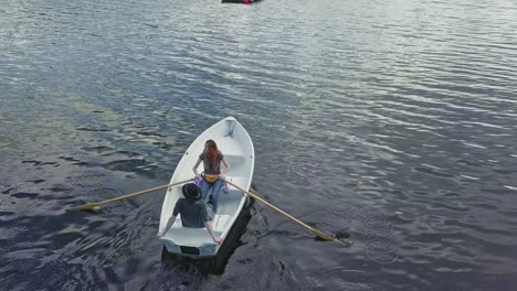 feminist free woman on a boat with paddle and relaxing man in a hat, aerial drone shot