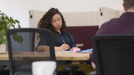 woman writing in notepad in office