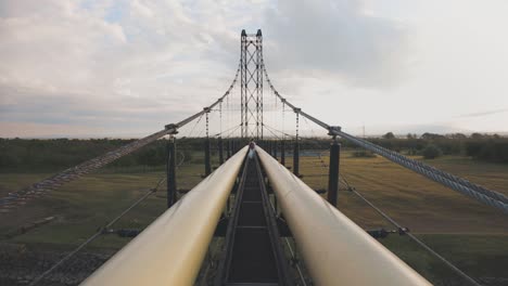 hombre caminando por un puente estrecho con una tubería de suministro de agua
