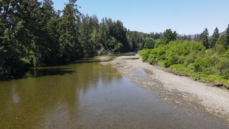 Drone-shot-of-flying-low-and-quickly-over-quiet-creek-on-an-early-summer-day-in-Sooke,-British-Columbia