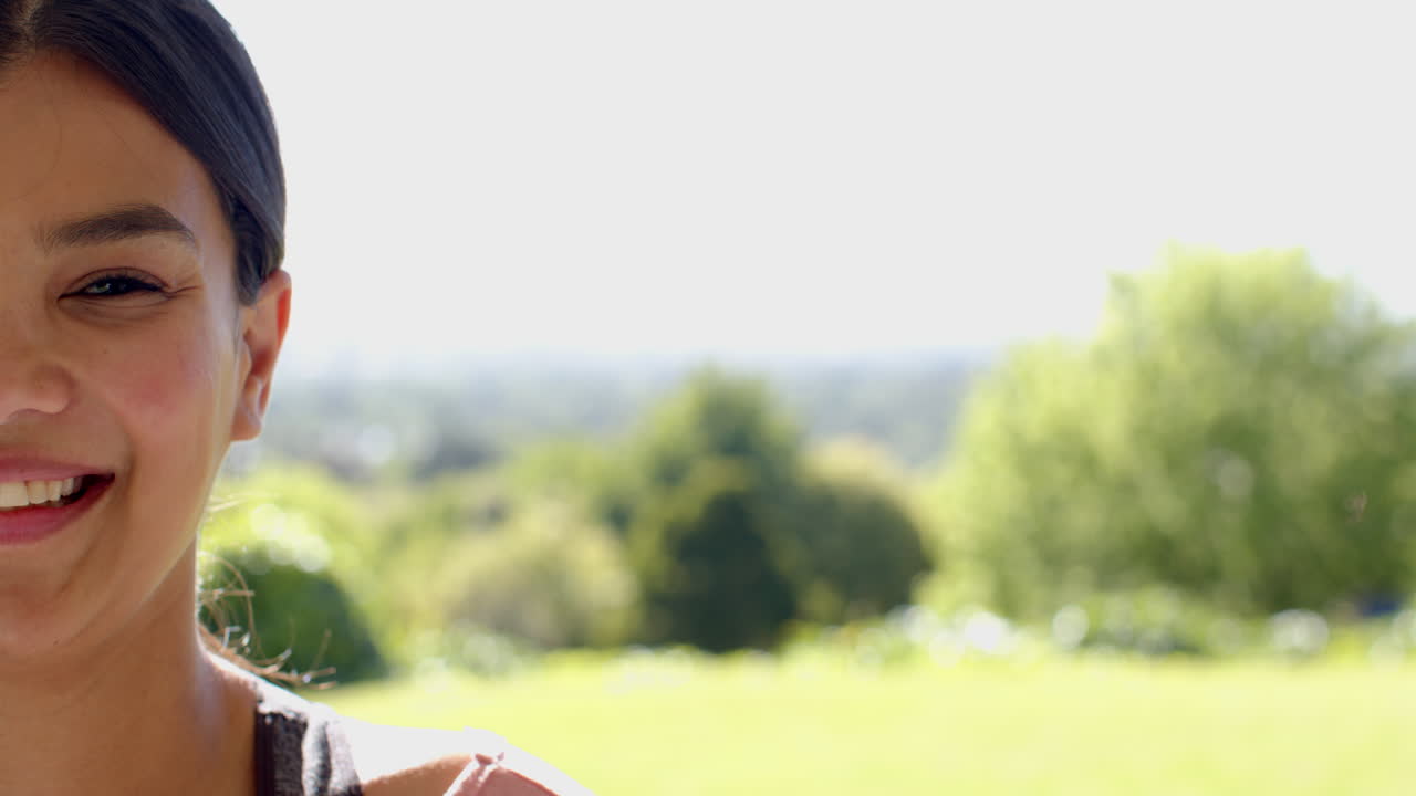 Smiling girl enjoying sunny day in lush green park, feeling joyful outdoors, copy space