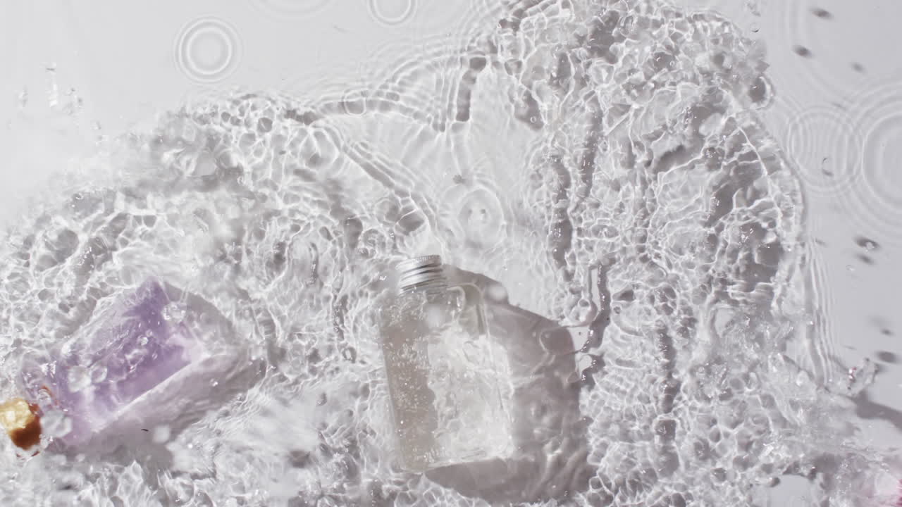 색 배경에 복사 공간과 함께 물에 있는 미용 제품 병의 비디오