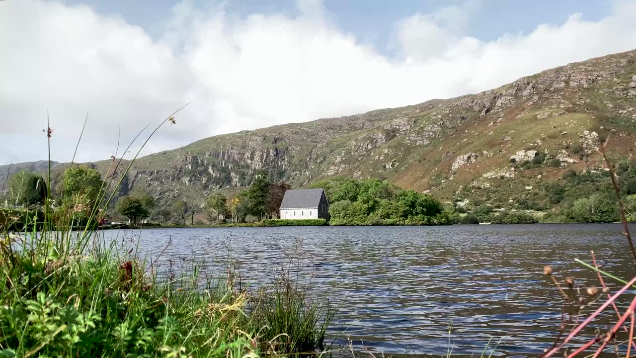 el lapso de tiempo de una capilla en un lago - gougane barra, irlanda