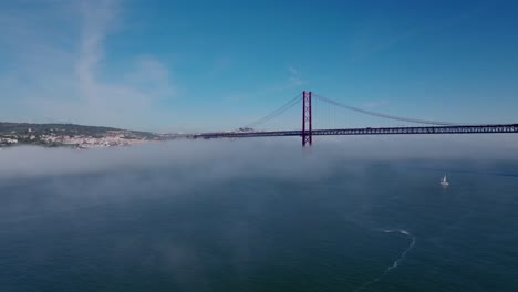 drone shot of clouds, fog, river and bridge (in lisbon).