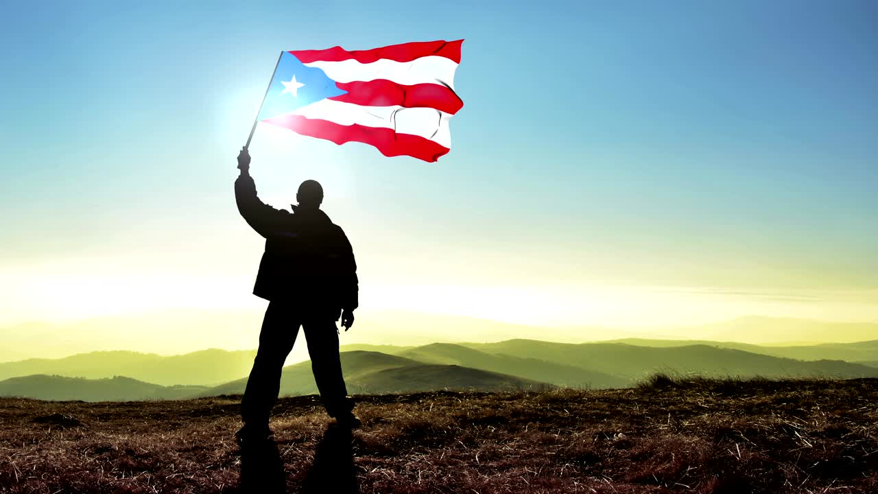 Successful silhouette man winner waving Puerto Rico flag on top of the mountain peak, Cinemagraph LOOP background