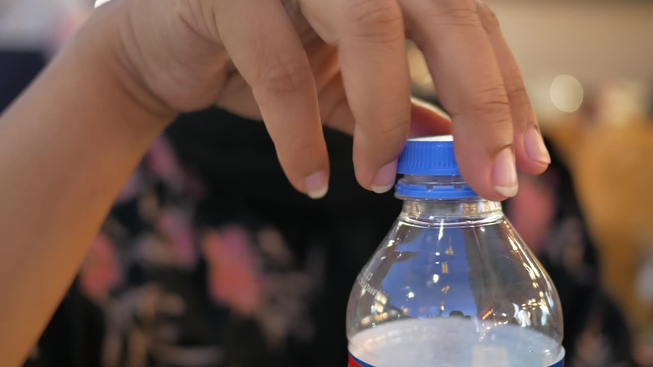 플라스틱 물 병 을 열고 있는 사람