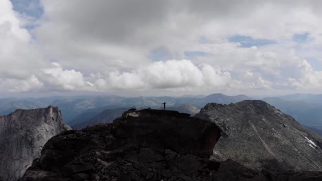 un hombre está de pie en la cima de una montaña.