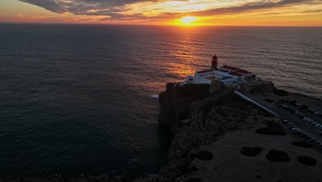 a dramatic aerial shot revealiing the lighthouse standing strong against the rugged cliffs and open ocean.