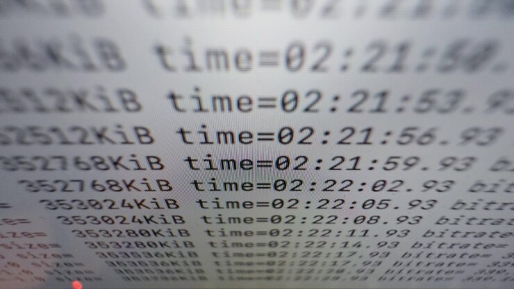 Computer screen displays rapidly updating technical information with changing time values and numerical data, illustrating automated processing, digital workflows and information technology.