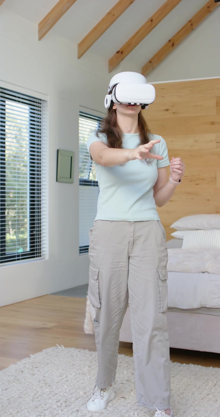 Video verticale: Donna che reagisce a un comando dell'auricolare in camera da letto, in maglietta e smartwatch, mentre esegue un gesto di pizzicamento.