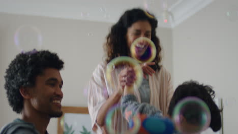 familia feliz jugando con burbujas de jabón en casa niño lindo divirtiéndose con su madre y su padre disfrutando de un juego juguetón la mañana del fin de semana 4k