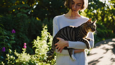 woman walking with her cat in a sunlit garden