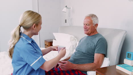 Nurse-Brings-Hot-Drink-To-Senior-Man-On-Home-Visit