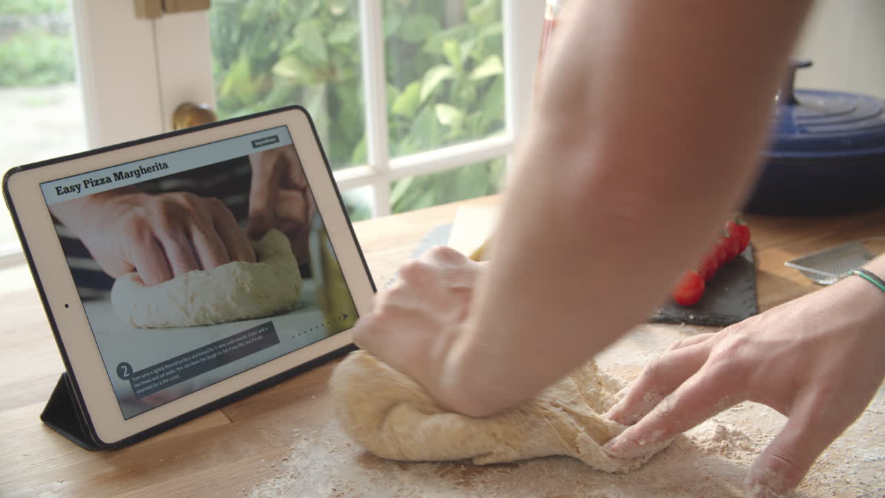 persona que sigue la receta de la pizza usando una aplicación en una tableta digital