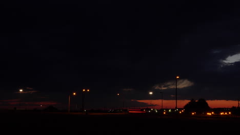 time-lapse shot of dramatic storm clouds after sunset with traffic and street lights