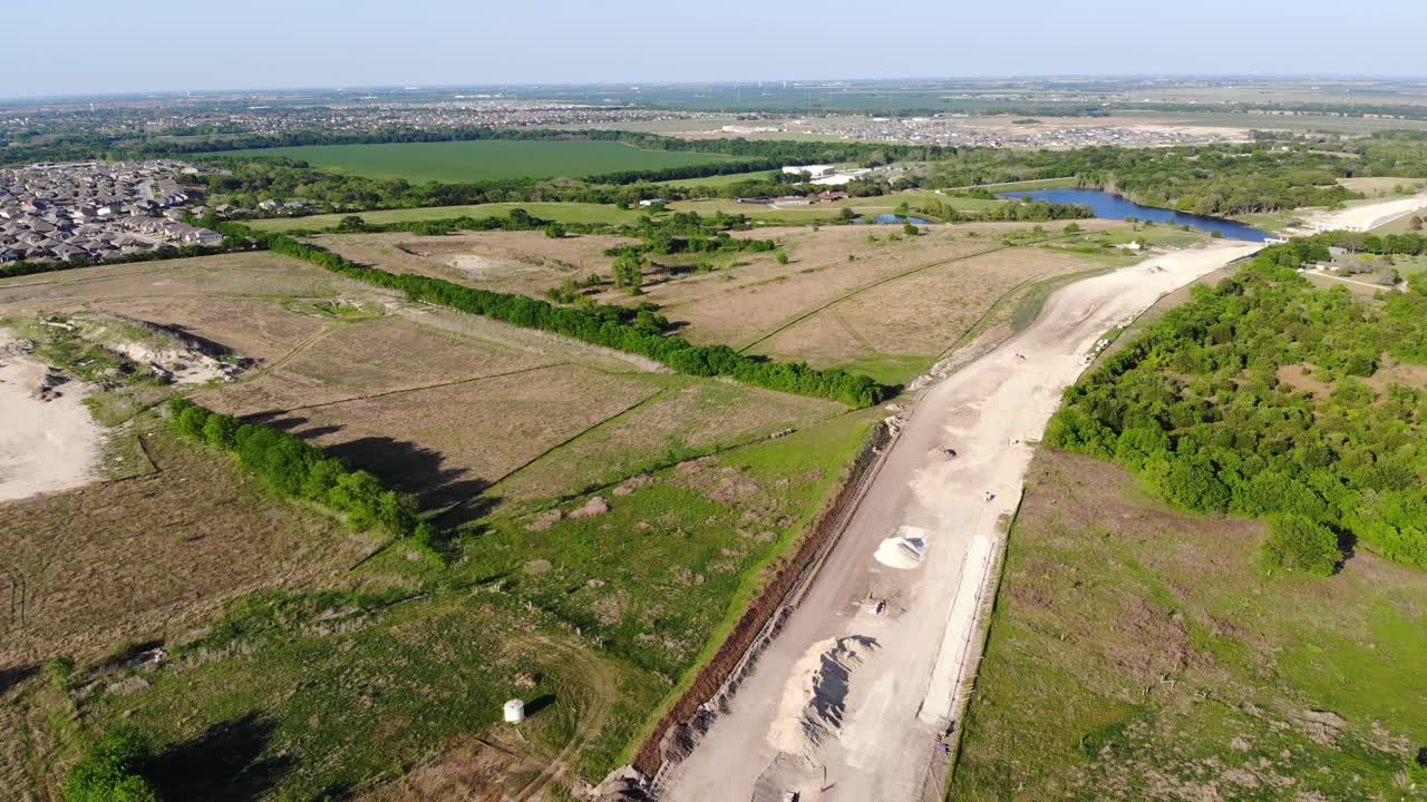 moviéndose hacia una gran extensión de carretera que se está construyendo a través del campo