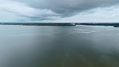 Wide-shot-of-an-open-lake-with-forest-in-the-background-on-an-overcast-day-with-clouds-reflecting-on-the-water