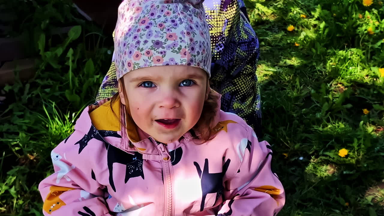 Smiling girl in pink jacket and floral hat enjoys playful moment with her brother