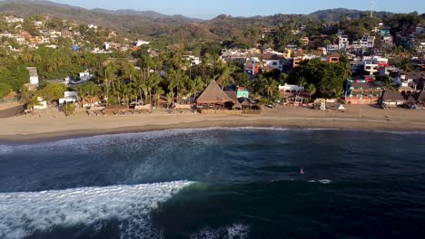 vista aérea de sayulita durante la puesta de sol con surfistas en el agua