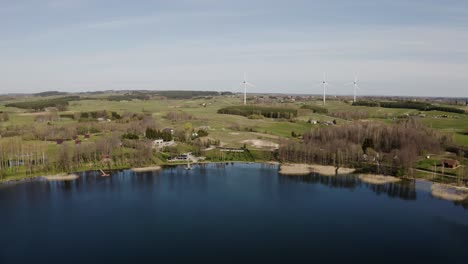 Flug-über-Einen-See-Im-Frühling-Mit-Windgeneratoren-Im-Hintergrund