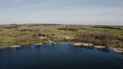 volando sobre un lago en primavera con generadores de viento en el fondo