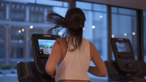 Junge-Frau-Trainiert-Nachts-Cardio-Auf-Dem-Laufband-Im-Fitnessstudio-Mit-Großen-Fenstern-Vor-Ihr-Und-4K-Kamerabewegungen