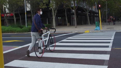 Hombre-Asiático-Con-Mascarilla-Y-Bicicleta-Cruzando-La-Calle