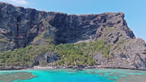 aerial trucking shot of rocky cliffs with turquoise caribbean sea with coral reefs in dominican republic