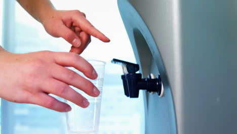 mujer ejecutiva bebiendo agua del purificador de agua