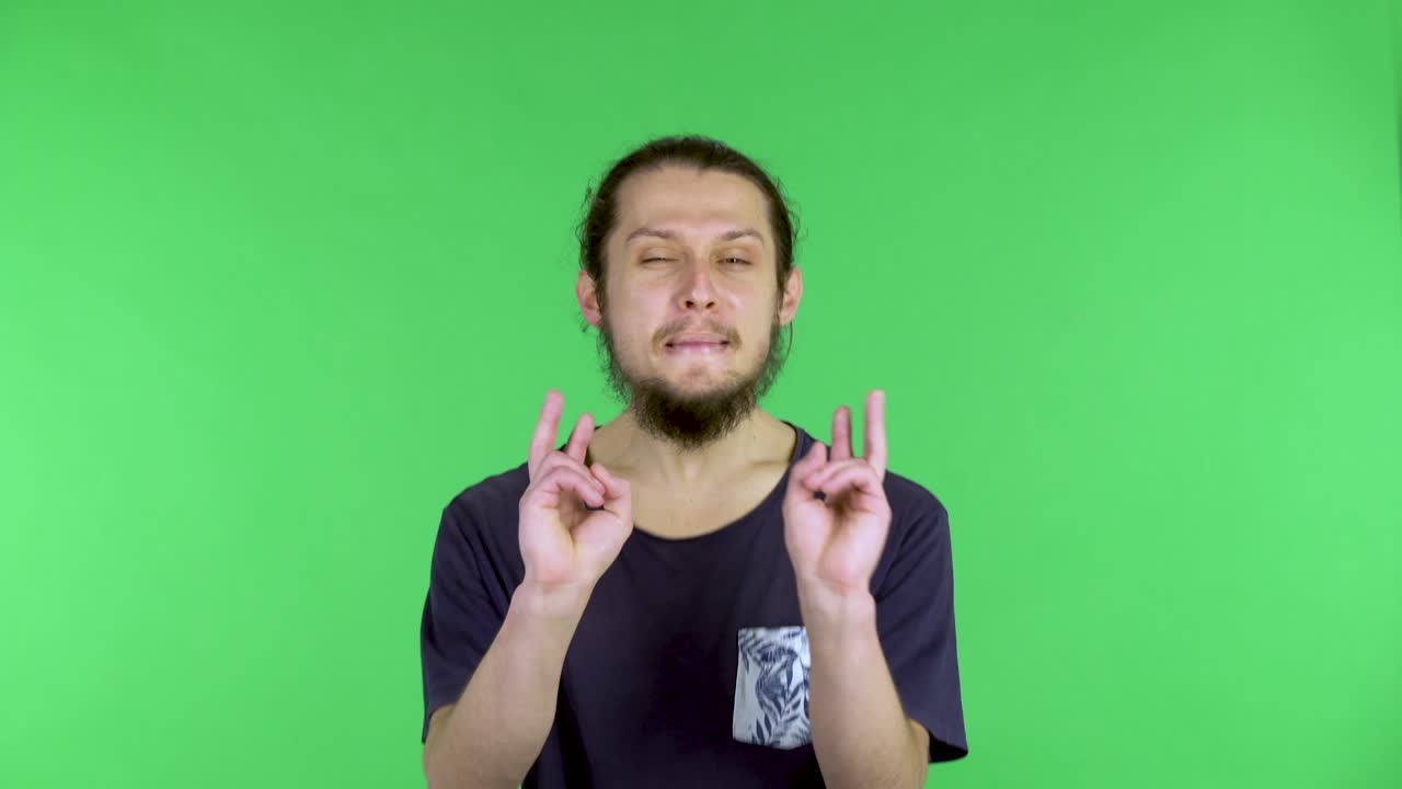retrato de un joven muestra un gesto de victoria con dos dedos. un gesto de aprobación, paz, amabilidad, saludo. hombre de pelo oscuro barbudo en el estudio en una pantalla verde. cerca
