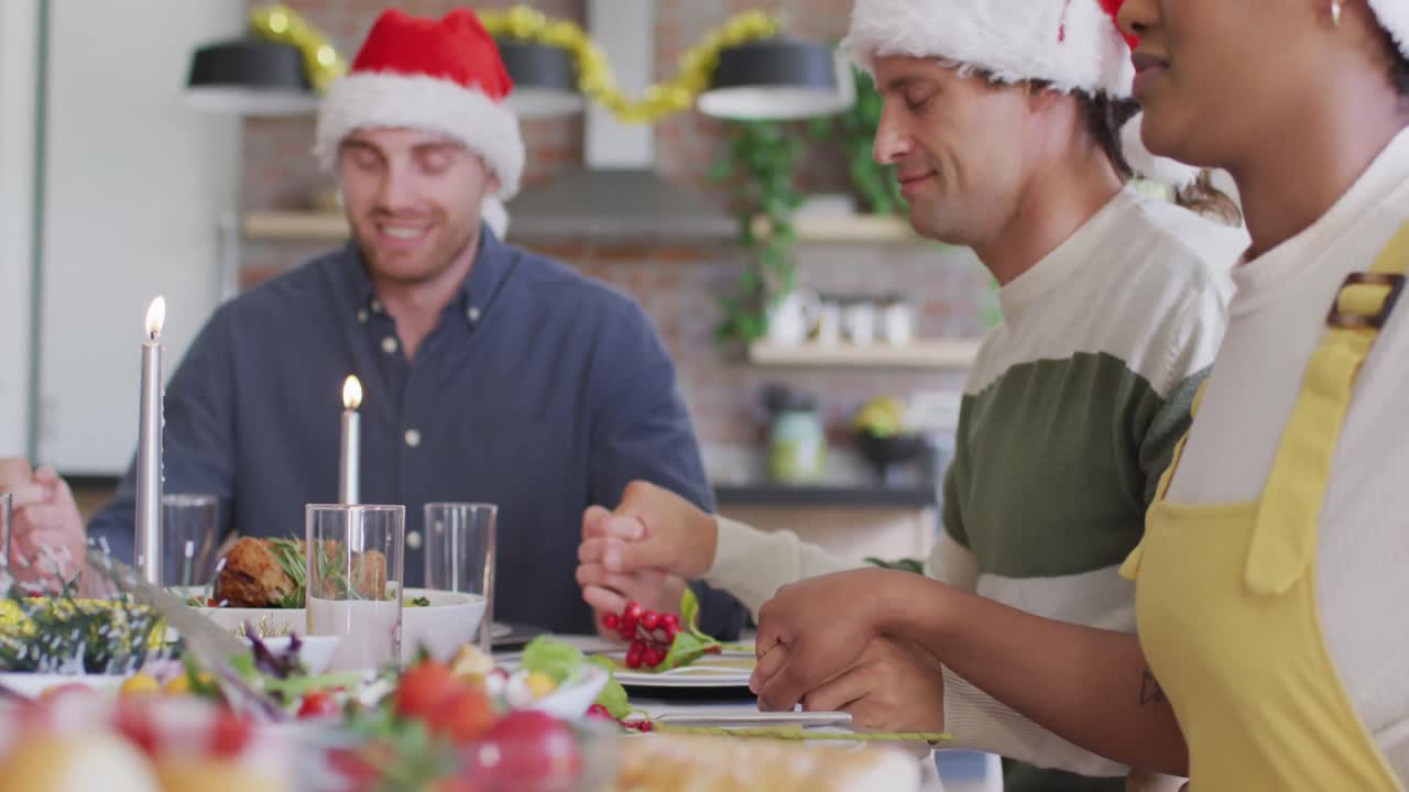 grupo feliz de diversos amigos en sombreros de santa celebrando la comida en tiempo de navidad
