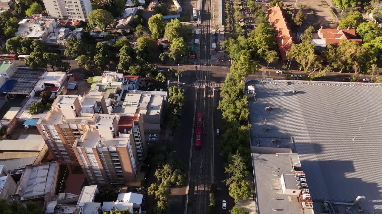Aerial over capital city of Argentina, Mendoza city during sunset showing red tram moving through the bustling urban streets.
