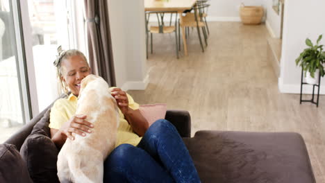 Mujer-Mayor-Afroamericana-Sentada-En-El-Sofá,-Acariciando-A-Un-Perro,-Riendo