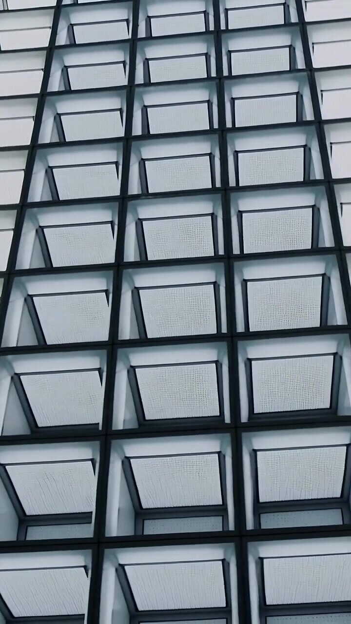 Vertical video: Tilting handheld camera panning up at street-level facade, revealing metal mullions