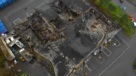 aerial view of damaged warehouse building with burnt roof, zoom out