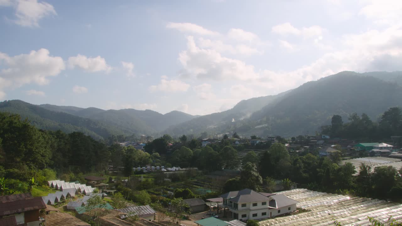 Panoramic view of a rural village and greenhouses nestled in a mountain valley