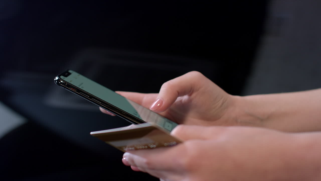 mujer con una tarjeta de crédito en la mano y usando un teléfono inteligente para comprar en línea