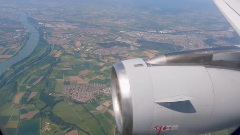 Airplane-windows-in-flight-turbine-in-closeup-Flying-over-important-river-in-Germany-between-two-cities