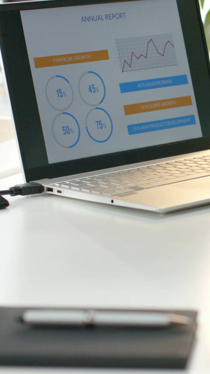 Vertical video: Camera panning revealing laptop report and monitor, showing desk setup