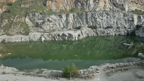 green water reflects the rocky landscape of the abandoned can rovira quarry near barcelona, sant fost, creating a serene yet industrial scene