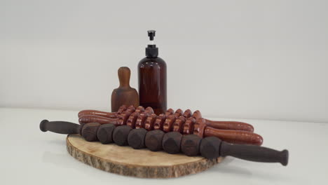 Set-of-wooden-tools-with-different-types-of-rollers,-cup,-paddles-and-oil-for-wood-therapy
