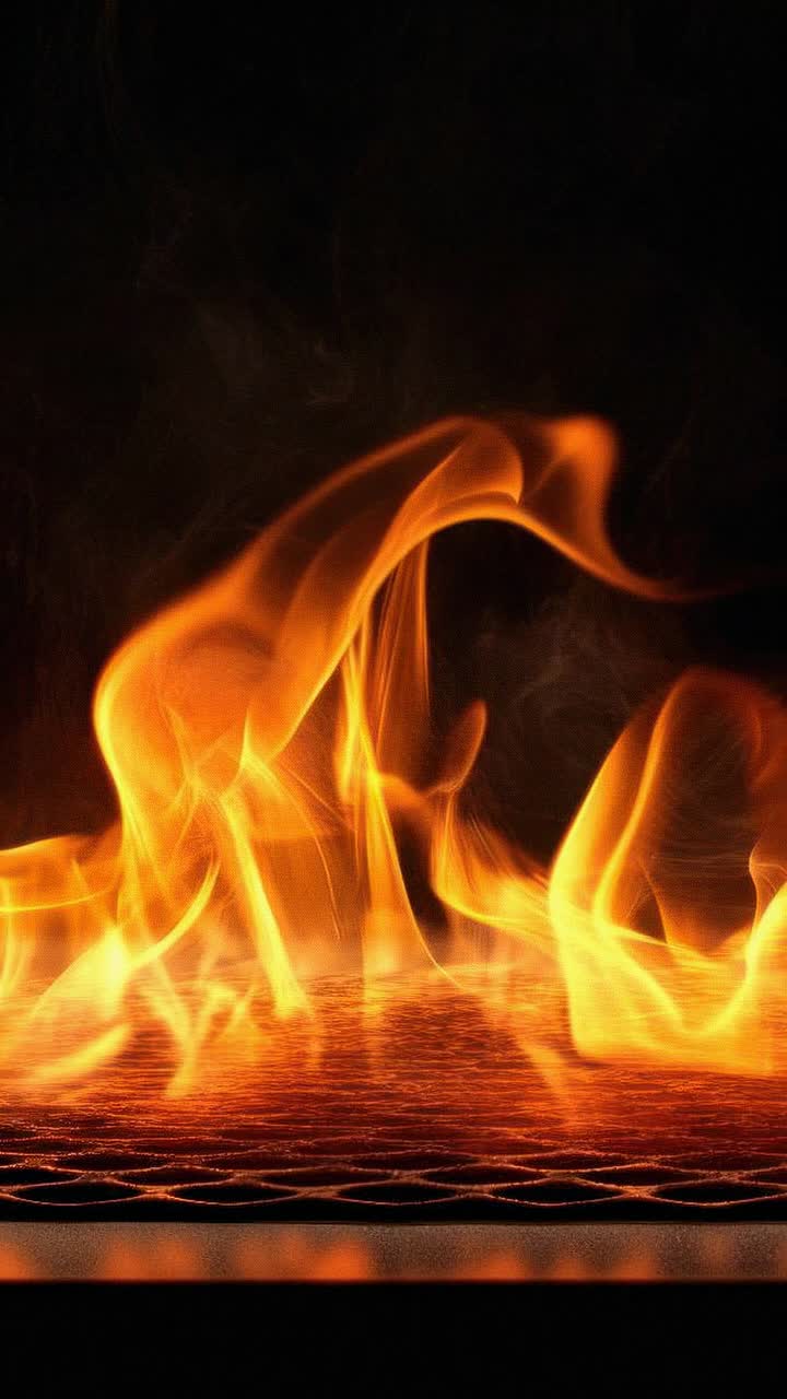 Video ravvicinato di fiamme vivaci che danzano su una griglia, ripreso da un angolo basso