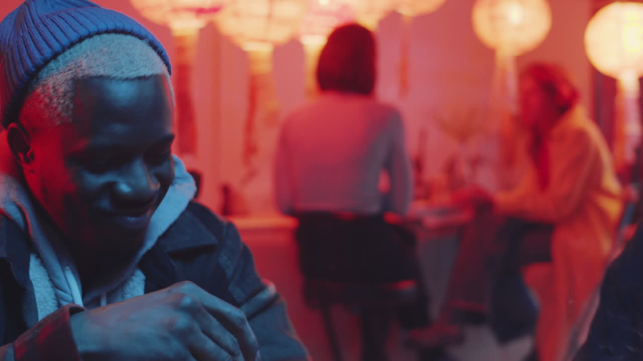 hombre transgénero feliz charlando con amigos multiétnicos en un bar