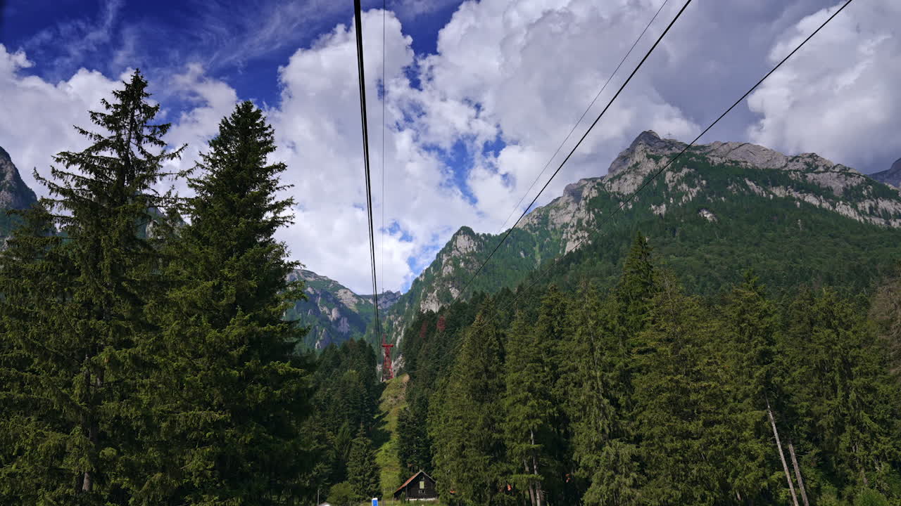 Moving along the tops of the evergreen pine-trees on the funicular. Riding Busteni Cable car to admire spectacular mountains under the fluffy cloudscape. Romania tour