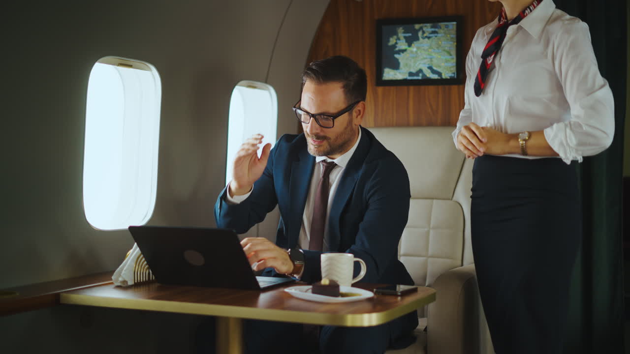 Businessman working on private jet with cabin crew