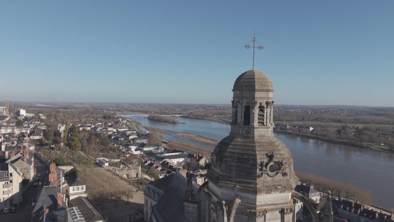 Una vista aérea de una torre de iglesia abovedada y ornamentada que se eleva sobre los tejados de un pueblo a lo largo del río Loira