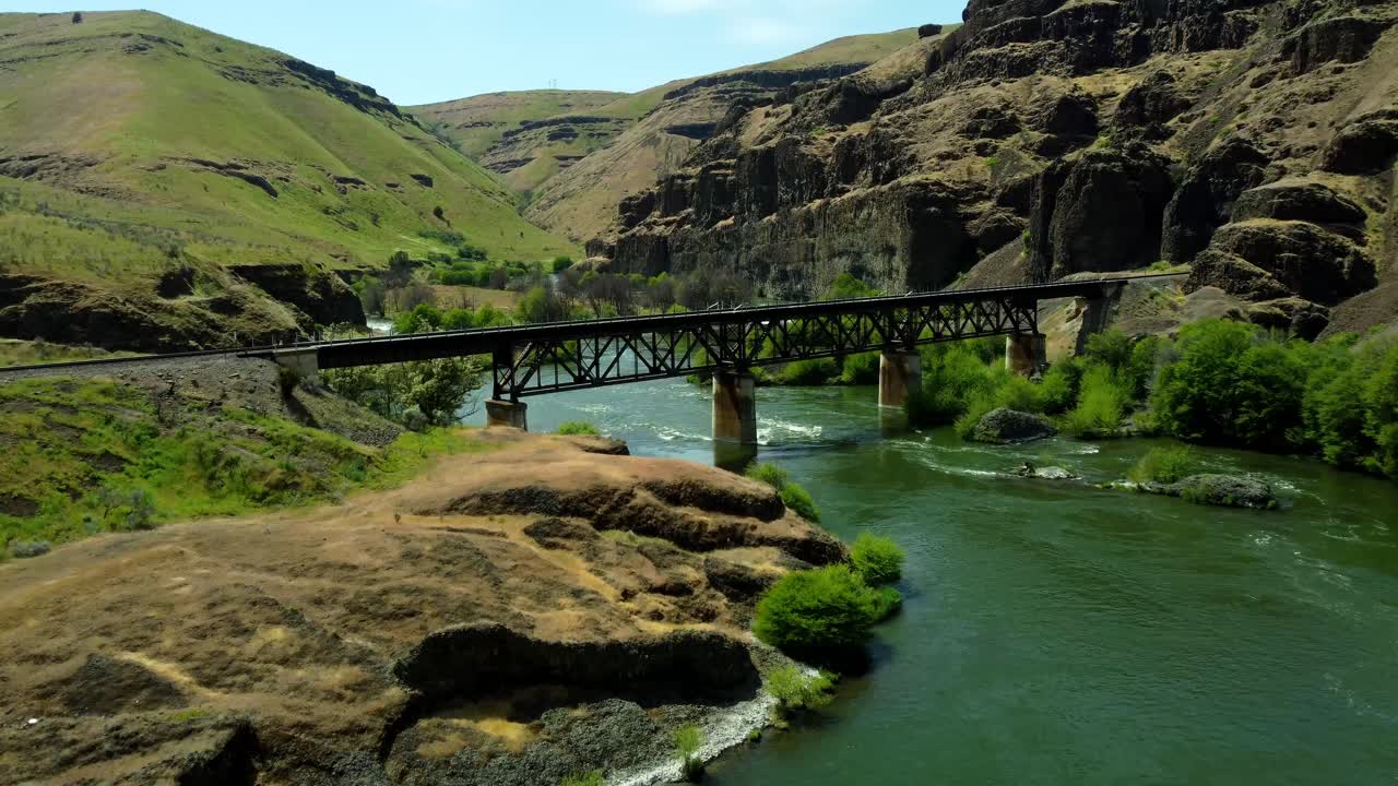 US, Oregon, Maupin, Deschutes River, 2025-05-08 - Drone view on the Deschutes River of a train bridge at Twin Crossings which is two bridges and a tunnel. In north central Oregon in spring