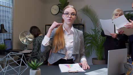 portrait of business woman in office looking camera doing phone gesture like says hey you call me