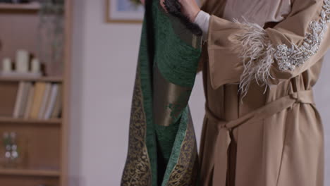 close up of muslim woman at home laying down prayer mat on floor