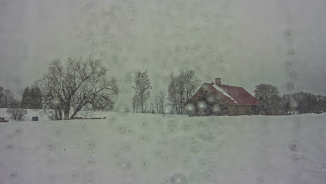 water drops on window in winter season with view to rural buildings, fusion time lapse